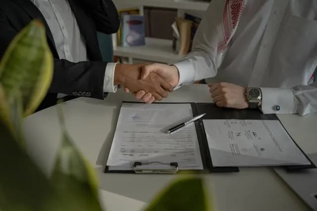 Two people shacking hands at a desk