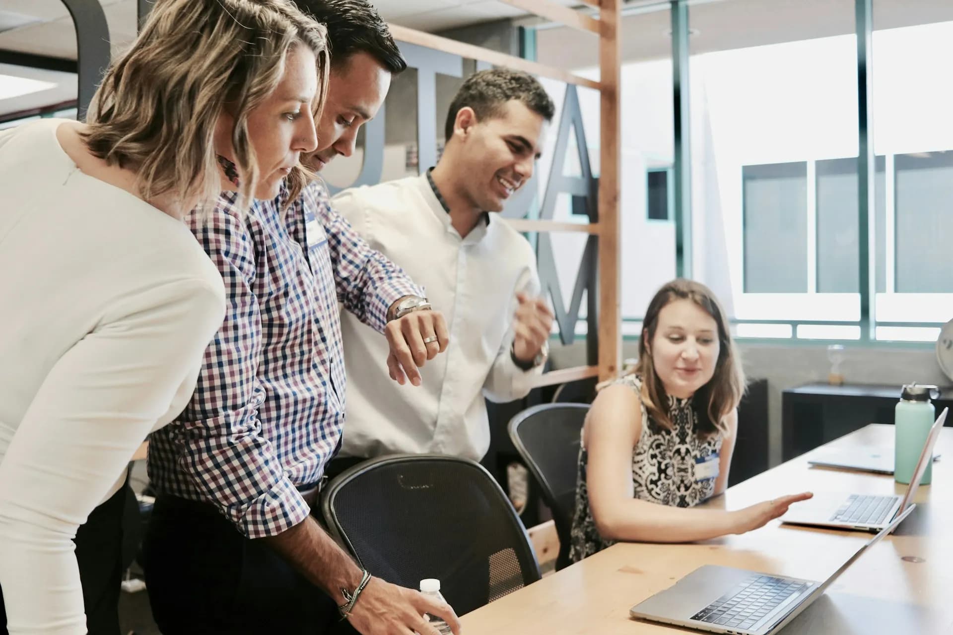 A woman sitting at table with a laptop explaining something to her colleagues