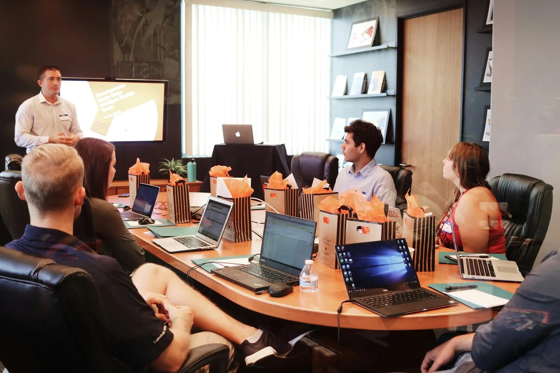 A man standing in front of people sitting beside table with laptop computers